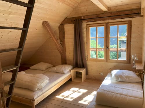 Cozy wooden bedroom at Les Chalets de l'Eau Rousse with two beds, mountain views, and rustic Alpine charm in Celliers, France
