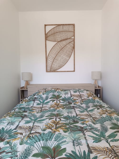 Chambre aux accents tropicaux au cottage ART DE VOYAGER avec literie botanique et décoration murale en feuilles tressées