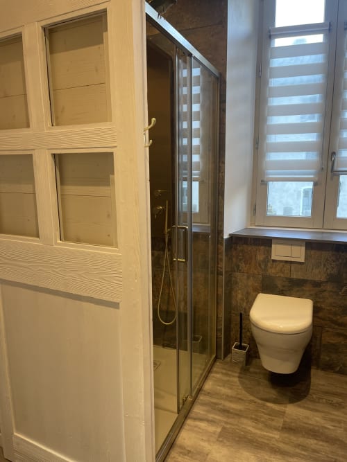 Salle de bain moderne à La Montagnette BnB à Moutiers avec douche vitrée, toilettes murales et fenêtre.