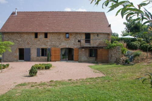 Maison en pierre aux Chambres d'hôtes Les Pratges à Figeac, avec toit en terre cuite, portes en bois et jardins entretenus