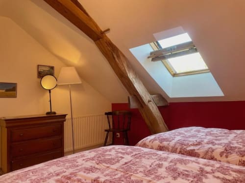 Chambre douillette sous les combles du Château de Vaux Morvan avec lits jumeaux, poutres apparentes, lucarne et vue sur le jardin
