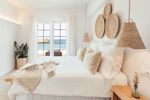 Dormitorio costero luminoso con ropa de cama blanca, decoración tejida y vistas al mar en Las Golondrinas, Cap d'Artrutx