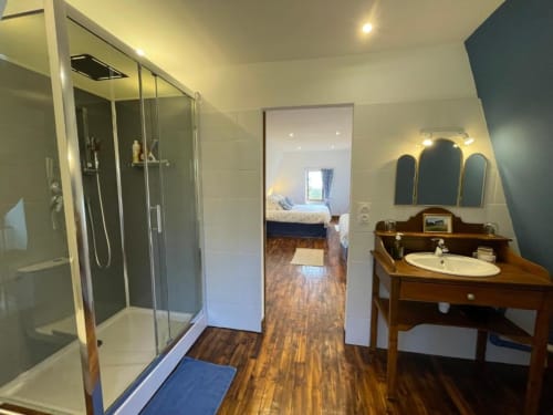 Salle de bain spacieuse avec douche à l'italienne, vasque en bois et miroir au gîte Château de Vaux Morvan