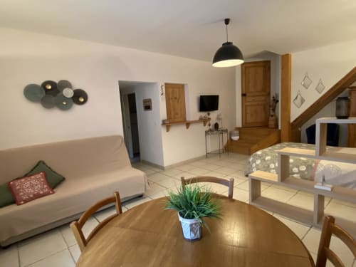 Séjour du gîte Le Cocon avec table à manger, canapé, télévision et escalier en bois à Chanos-Curson