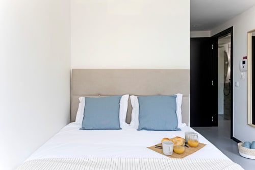 Moderno e compacto quarto estúdio no hotel Porto com almofadas azuis, roupa de cama branca e bandeja de café da manhã