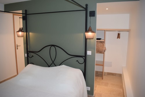 Chambre moderne avec lit à baldaquin noir, literie blanche, mur d'accent vert sage et luminaires suspendus aux Chambres d'hôtes