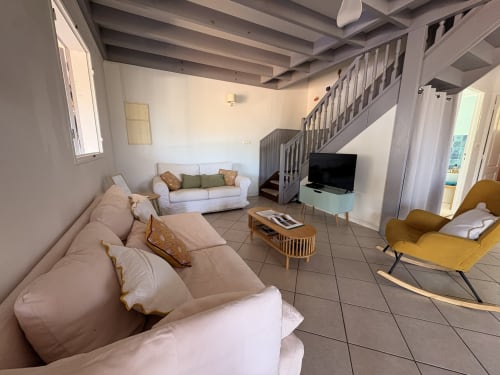 Spacieux séjour de la villa La Villa Maraloupia aux Avirons avec vue sur mer, canapés, TV et escalier