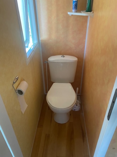 Toilettes blanches immaculées dans salle d'eau compacte aux murs pêche au camping-car Le Relais de La Mirpe à Bergerac