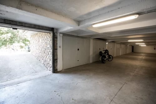 Garaje subterráneo del Complejo Front Beach con unidades de almacenamiento y motocicleta estacionada en Montgat