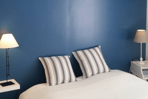 Chambre moderne à la villa Mer et Maisons avec mur d'accent bleu, oreillers rayés, literie blanche et lampes de chevet