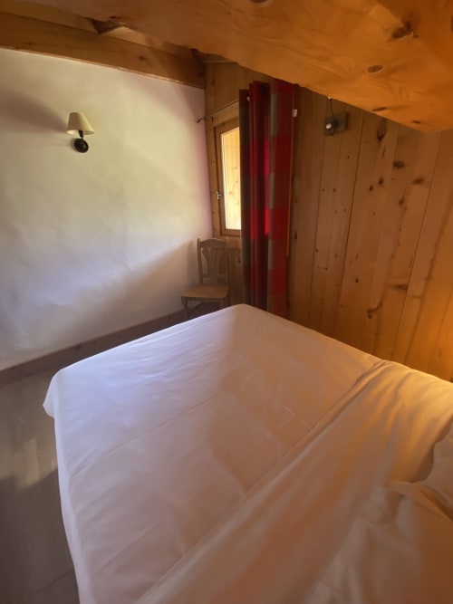Chambre aux draps blancs dans un appartement aux murs en bois à La Ferme des Georgières, Notre-Dame-de-Bellecombe