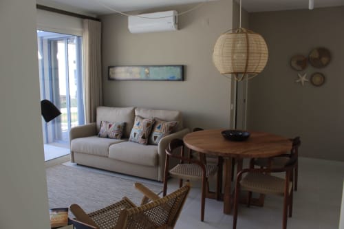 Modern apartment living room at Break Lovers in Tavira with beige sofa, wooden dining table, woven pendant light, and sea