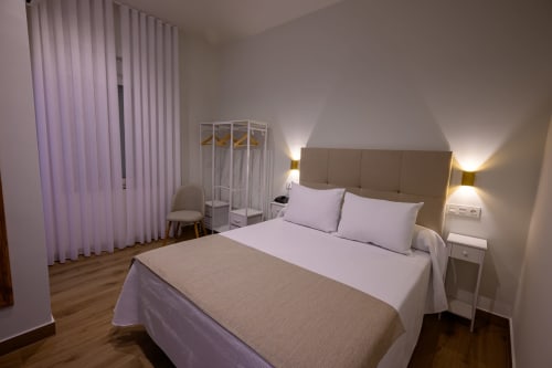 Habitación moderna en Hotel Boutique Alcazaba Salobreña con cama queen, vistas al jardín, cortinas moradas e iluminación ambiental
