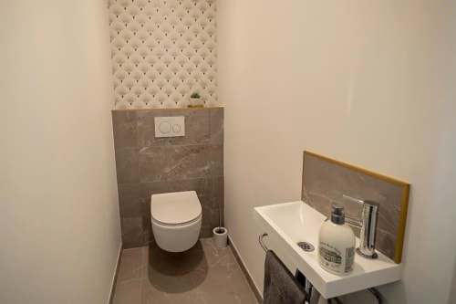 Salle de bain moderne du gîte Loft Le Chic avec toilettes murales, lavabo et carrelage en marbre gris à Gîtes Saint Valery En Caux