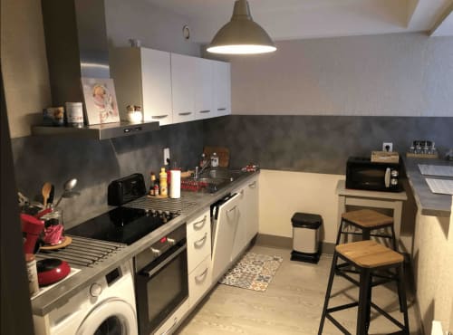 Cuisine moderne de l'appartement Le Paillot de Montabert à Troyes avec armoires blanches, électroménagers inox et coin repas