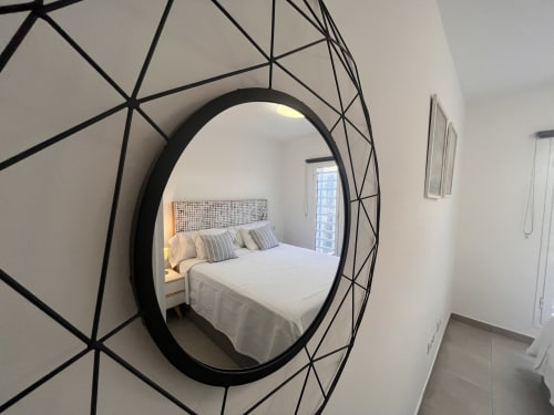 Modern circular mirror reflecting bedroom with white bedding at FTV Holidays Homes in Corralejo