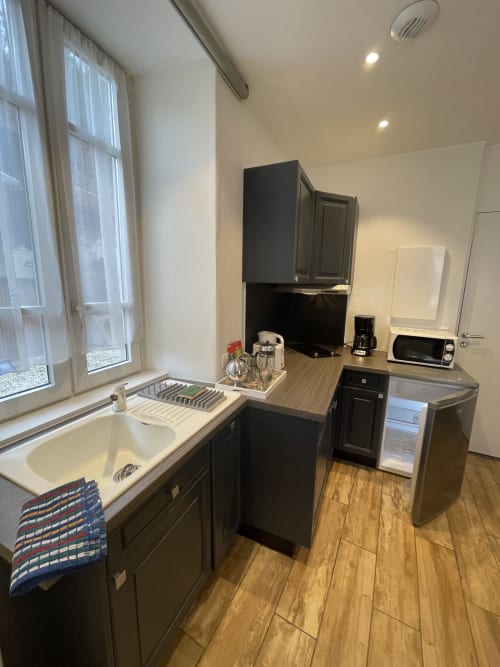 Petite cuisine de l'appartement La Montagnette à Moutiers avec meubles noirs, évier, micro-ondes et cafetière