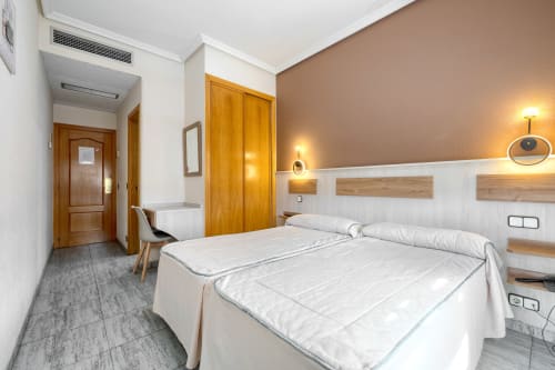 Moderna habitación doble en Hostal El Molino, Collado Villalba, con dos camas, armarios de madera y decoración contemporánea