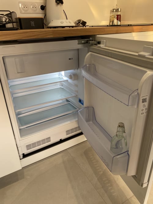 Réfrigérateur blanc ouvert avec étagères vides dans l'appartement Studio 5 de La Maison Blanche, Bouguenais