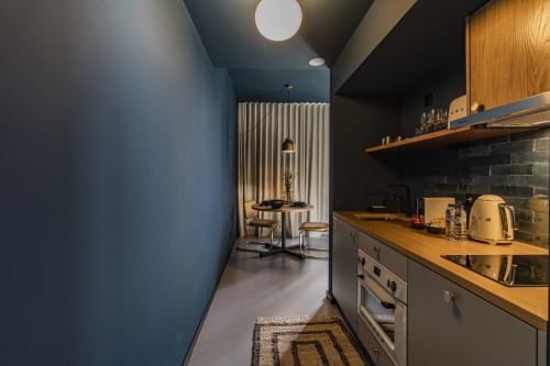 Cozinha moderna em apartamento de hotel no Porto com bancadas de madeira, armários escuros, eletrodomésticos em aço inoxidável e paredes com destaque azul