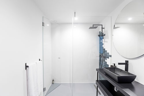 Modern bathroom in Benefit Collection Porto studio apartment with black vessel sink, round mirror, rainfall shower, and white