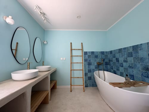 Salle de bains moderne de La Villa Maraloupia avec murs turquoise, double vasque, baignoire îlot et carrelage bleu