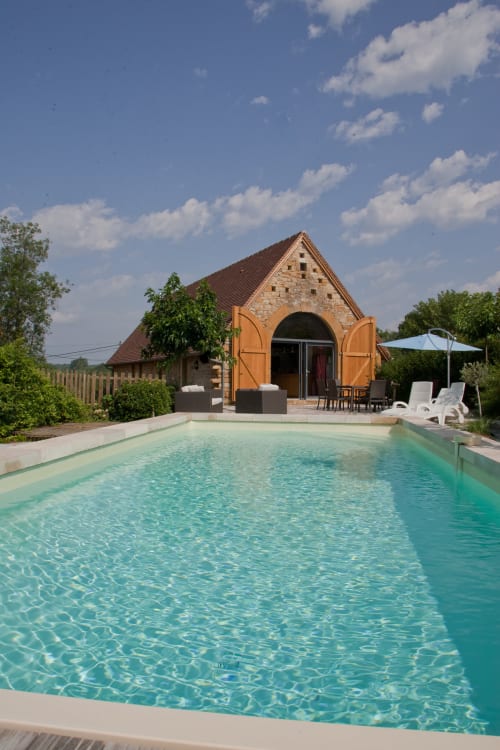 Piscine turquoise, maison en pierre et portes cintrées orange aux Chambres d'hôtes Les Pratges, Figeac