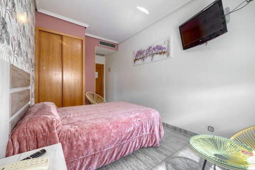 Luminosa habitación doble en Hostal El Molino de Collado Villalba con ropa de cama rosa, armario de madera, aire acondicionado, TV pantalla plana y