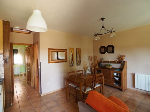 Comedor luminoso en apartamento rural español con muebles de madera, iluminación colgante y vista al jardín