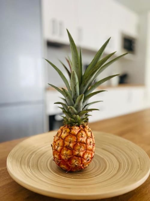 Piña fresca en plato de madera en la cocina de un apartamento rural en La Palma con fondo blanco moderno