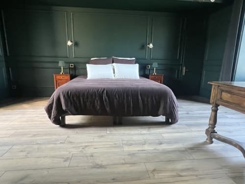 Spacieuse chambre avec lit king-size, literie prune, murs vert foncé, tables de nuit en bois et parquet clair à La Millière