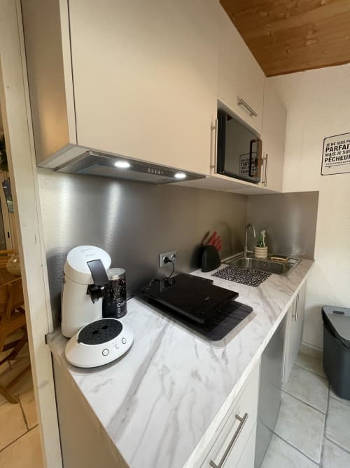 Kitchenette moderne avec plan de travail en marbre, électroménagers blancs, crédence en acier inoxydable à Cap d'Agde