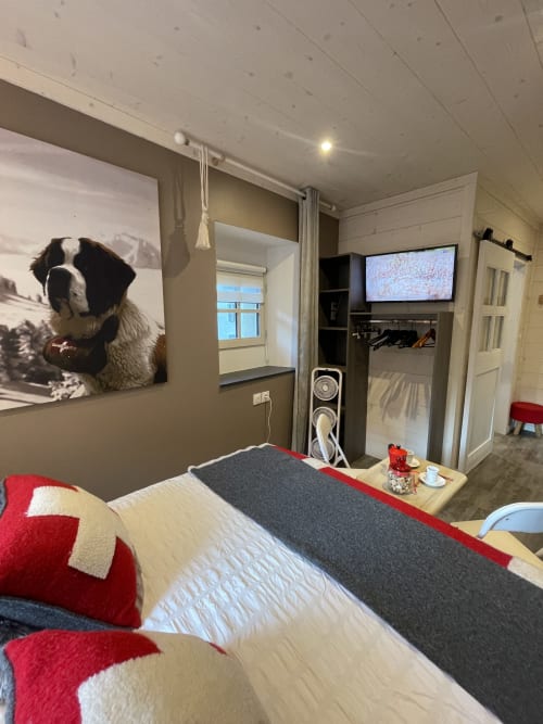 Chambre cosy du gîte La Montagnette à Moutiers avec lit, télévision et portrait de chien en œuvre murale