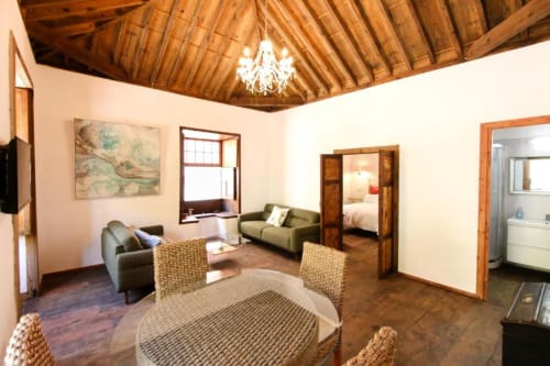 Amplia sala de estar en Casa 1820 de Rural La Palma con sofá, mesa de comedor, techo con vigas de madera y vistas al jardín