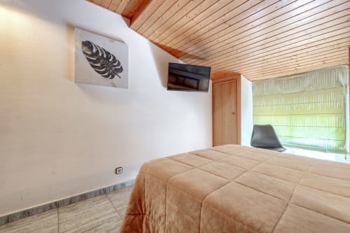Luminosa habitación en Hostal El Molino con cama queen, techo de madera, TV y persianas verdes en Collado Villalba