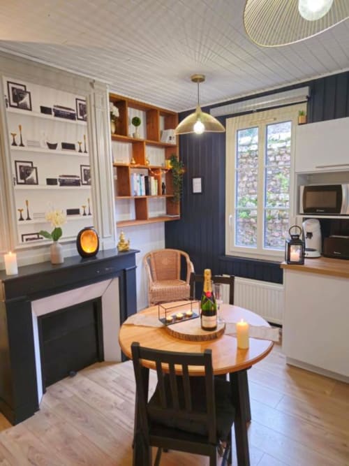 Cuisine-salle à manger moderne du gîte L'or Noir avec table ronde en bois, chaises noires, suspension dorée