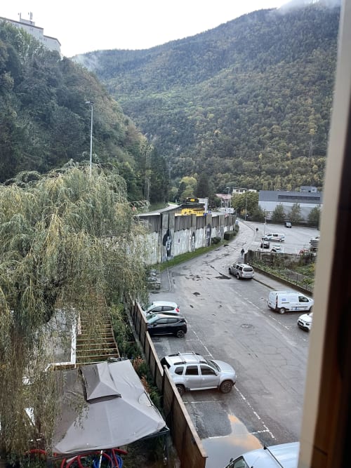 Vue depuis la chambre La Montagnette à Moutiers : zone de stationnement et vallée alpine forestière