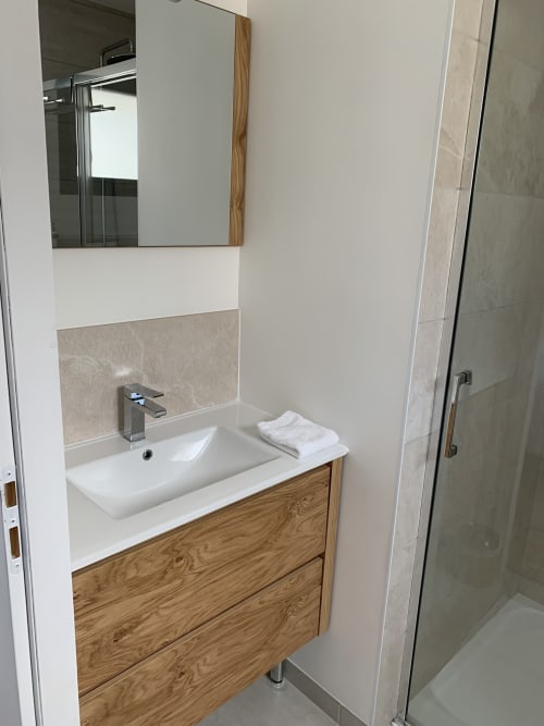 Modern bathroom with wooden vanity, white sink, mirror, and glass shower at La Maison Blanche BnB in Bouguenais, France