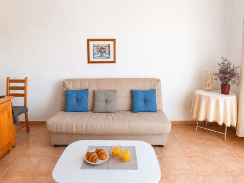 Beige sofa with blue and gray pillows in bright living room at Apartamentos El Calón Playa, Cuevas del Almanzora