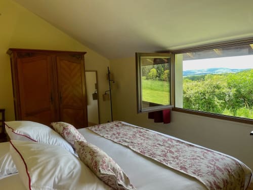 Chambre lumineuse du Château de Vaux Morvan avec vue sur le jardin, mobilier en bois et paysage champêtre