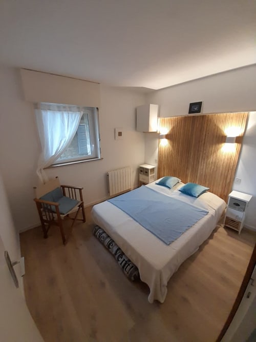 Chambre lumineuse à Mer et Maisons, La Trinité sur Mer, avec lit double, tête de lit en bois, fauteuil et fenêtre
