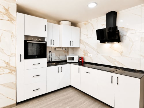 Cocina moderna blanca con encimeras negras y salpicadero de mármol en Apartamento Lateral Perla, Cuevas del Almanzora