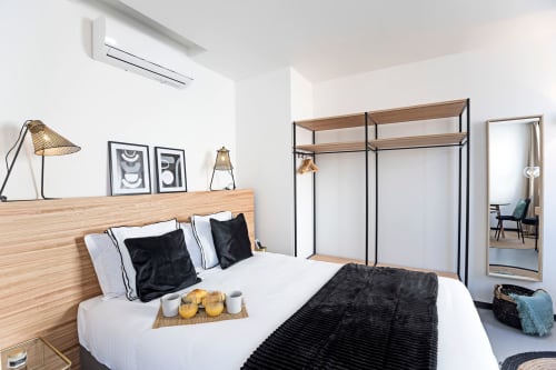 Quarto moderno do hotel Porto com cama de madeira, almofadas pretas, lençóis brancos, guarda-roupa com estrutura metálica e decoração minimalista