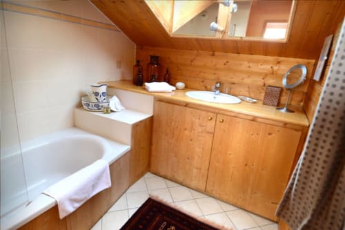 Salle de bain de la chambre Meridian à l'Auberge Nemoz, avec meuble vasque en bois, baignoire blanche avec porte-serviettes et puits de lumière