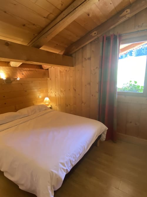 Chambre douillette à La Ferme des Georgières avec lit queen-size, éclairage chaleureux et vue sur les montagnes