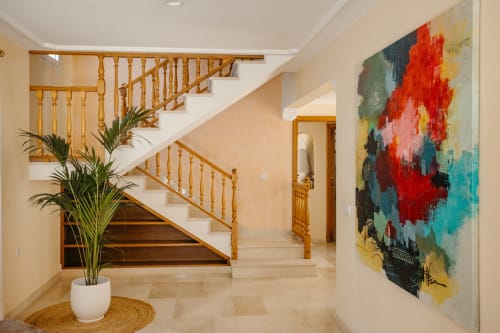 Entrada moderna de Las Golondrinas con escalera de madera, obra de arte abstracta y planta en maceta