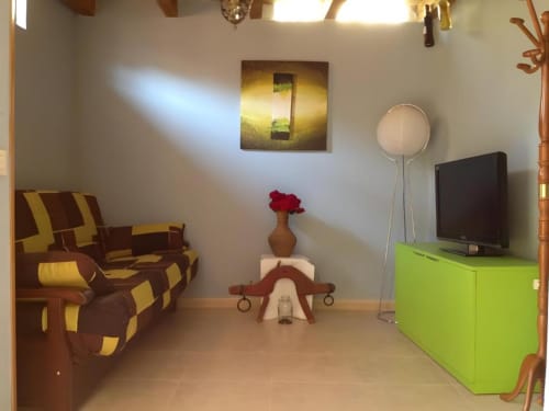 Sala moderna de Casas Rurales La Viña con sofá de rayas doradas y marrones, mueble TV verde lima y decoración contemporánea