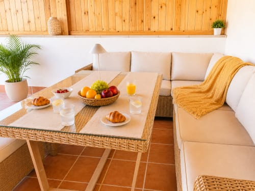 Canapé beige, table en bois, corbeille de fruits frais, croissants et boissons dans un lumineux appartement chez Sara & Gino