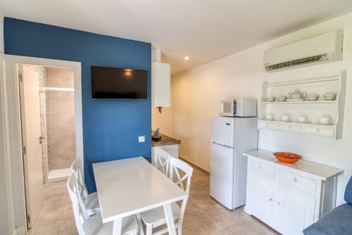 Moderna sala comedor con pared azul, electrodomésticos blancos, mesa y baño en apartamento Las Golondrinas
