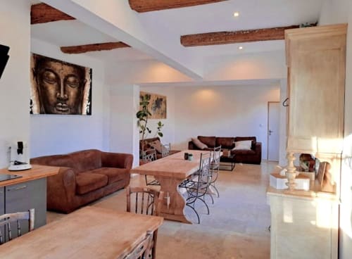 Spacieux séjour ouvert au cottage Chez Laure & Marc avec poutres en bois, canapé en cuir marron et table à manger avec piscine
